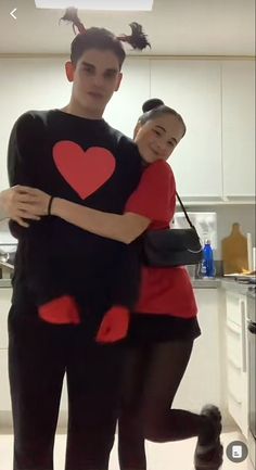 a man and woman are dressed up in costumes with hearts on their shirts, arms around each other