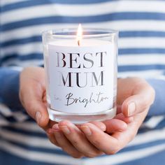 a woman holding a candle in her hands with the words best mum written on it