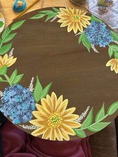 a wooden table with flowers painted on it's top and some other items nearby