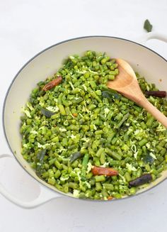 green beans and broccoli in a pan with a wooden spoon