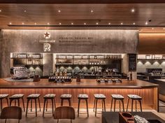 an empty restaurant with wooden tables and stools in front of the counter, along with bar seating