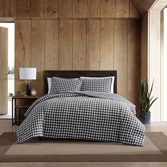 a black and white checkered comforter set in a room with wood paneling