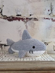 a crocheted stuffed shark sitting on top of a table