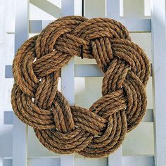 a rope wreath is hanging on the side of a white fence