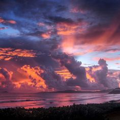 the sun is setting over the ocean and clouds