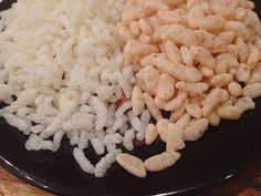 rice and cereal are on a black plate with a wooden table in the back ground