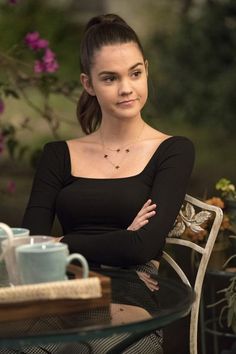 a woman sitting at a table with her arms crossed and looking off to the side