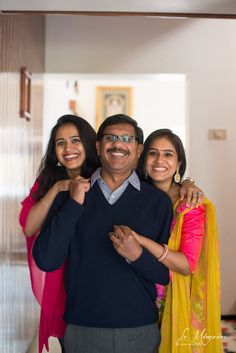 two women and a man are posing for a photo in the hallway with their arms around each other