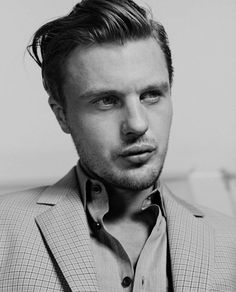 a black and white photo of a man in a suit looking at the camera with a serious look on his face