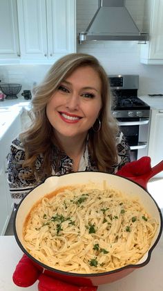 a woman is holding up a dish of spaghetti