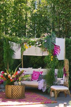 an outdoor seating area with lots of plants and flowers on the couch, surrounded by greenery