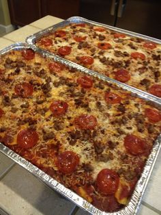 two pizzas sitting on top of metal pans covered in cheese and pepperoni