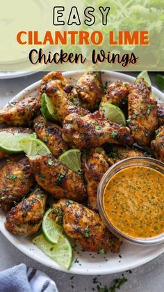 chicken wings on a white plate with dipping sauce and limes in the bowl next to it