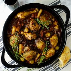 a skillet filled with chicken and potatoes on top of a table