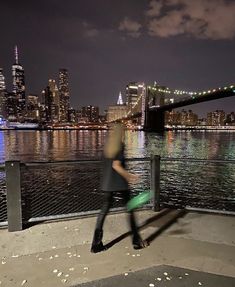 a man is walking down the sidewalk by the water