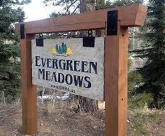 a sign for evergreen meadows in the woods