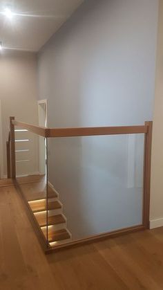 an empty room with stairs and hard wood flooring on the side, in front of a white wall