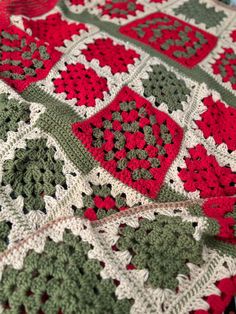 a crocheted blanket with red, green and white squares on top of it