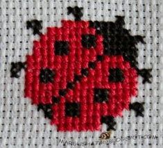 a cross stitch ladybug with black and red dots on it's back