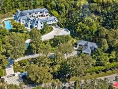 an aerial view of a large house surrounded by trees and bushes with a pool in the middle