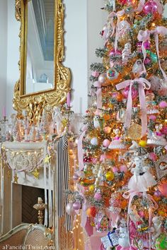 a decorated christmas tree with pink, gold and white ornaments in front of a mirror