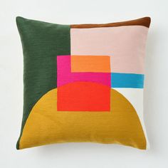 a pillow with an abstract design on the front and back, sitting on top of a white wall