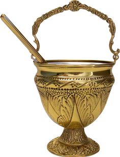 a gold colored metal bowl with a spoon in it and a handle on the top