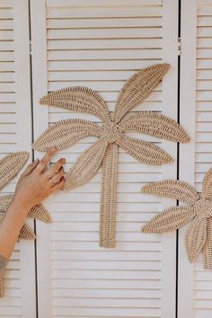 a person is making a palm tree out of wickers on the wall next to shutters