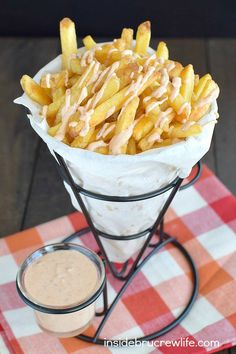 french fries in a basket with dipping sauce on the side and a small bowl of dip