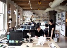 an office with people working at desks and computers on the tables in front of them