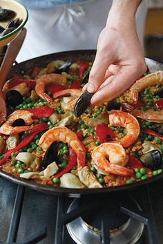 a person is cooking some food in a pan on the stove with shrimp and peas