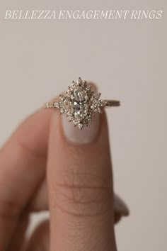 a woman's hand holding an engagement ring with a diamond center stone on it