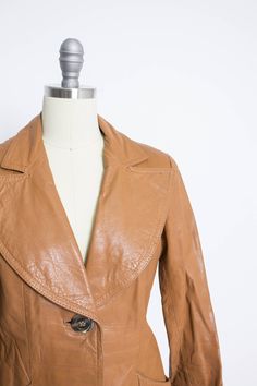 "Vintage 1970s cropped ladies leather jacket. Great quality leather is dyed a warn camel colored brown. Long sleeves, oversized notched collar. gently fitted waist, side pockets with a little sunburn design. Sunburst design is repeated on the back. Nylon quilted lining. Belt loops but no belt remains. Label: Wilson Fits like size: Small Measurements: Bust: 36\" Waist: 32\" Length: 23.5\" Sleeve length: 22.5\" Shoulder: 15\" Condition: Very good. Nicely broken in leather. Some normal wear on the Vintage Leather Outerwear For Spring, Fitted Brown Leather Jacket With Collar, Fitted Brown Leather Collared Jacket, Brown Collared Leather Jacket For Spring, Retro Leather Jacket For Spring, Spring Retro Leather Jacket, Vintage Leather Jacket For Spring, Vintage Leather Jacket With Lapel Collar For Fall, Vintage Leather Jacket For Spring Workwear