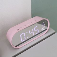 a pink alarm clock sitting on top of a table