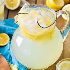 a pitcher filled with lemonade sitting on top of a table next to sliced lemons