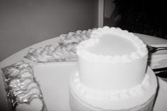 a white cake sitting on top of a table next to silver foil wrapped in plastic wrap