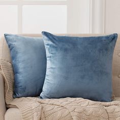 two blue pillows sitting on top of a couch