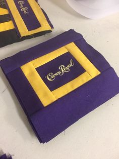 two purple and yellow napkins sitting on top of a white table next to each other