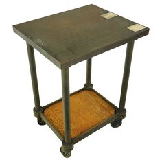 a small wooden table with wheels on the bottom and an open drawer underneath it that is holding a piece of wood