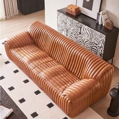 a brown leather couch sitting on top of a white rug next to a black table