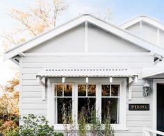 a small white house with an awning on the front door and windows that are open