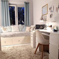 a living room with a couch, desk and chair next to a window in it