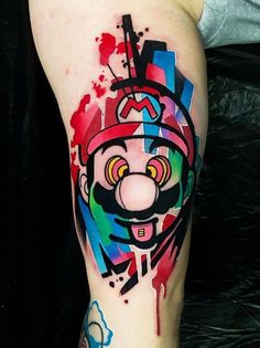 a colorful tattoo on the leg of a man with a clown face painted on it