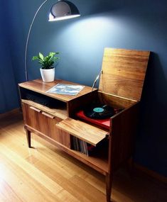 a record player is sitting on top of a wooden table with a lamp above it