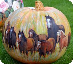 painted pumpkins with horses on them sitting in the grass