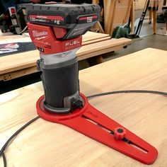 a corded electric driller on top of a wooden table with other tools in the background