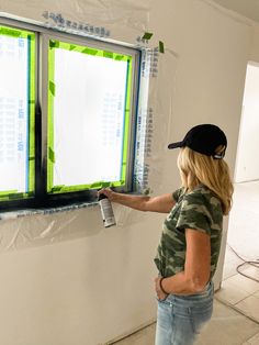 a woman painting a window with green and white paint