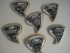 four decorated cookies with black and white icing on top of each cookie in the shape of a tornado