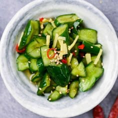 a white bowl filled with cucumbers and red peppers