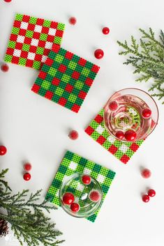 christmas coasters with red, green and white designs on them next to pine branches